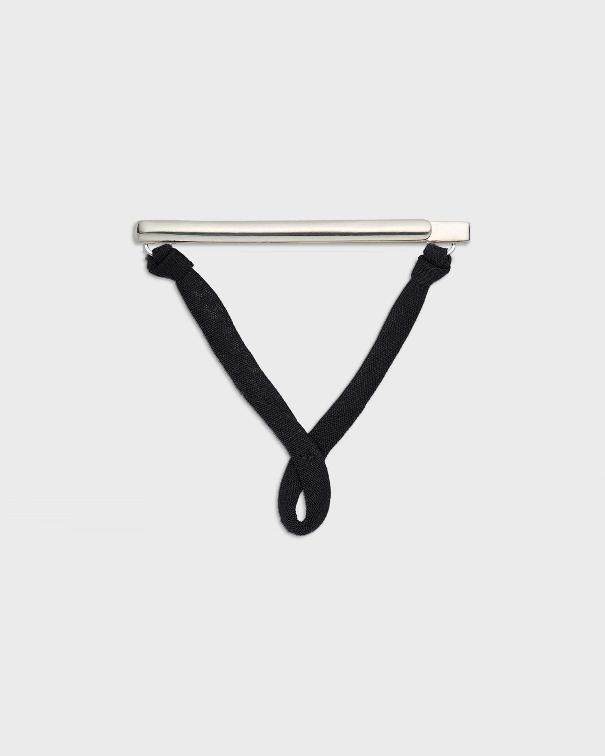 A minimalist silver bar pendant with black knotted cords hanging from its ends, displayed against a solid light gray background.